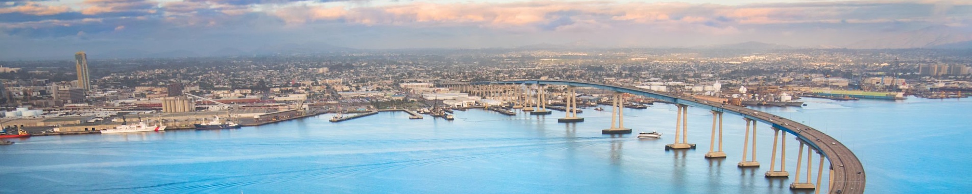The unique curvature of the Coronado Bay Bridge spanning San Diego Harbor joining two cities; San Diego and Coronado. I shot this image at dusk after a winter storm from a helicopter during a chartered photo flight at about 300 feet elevation.